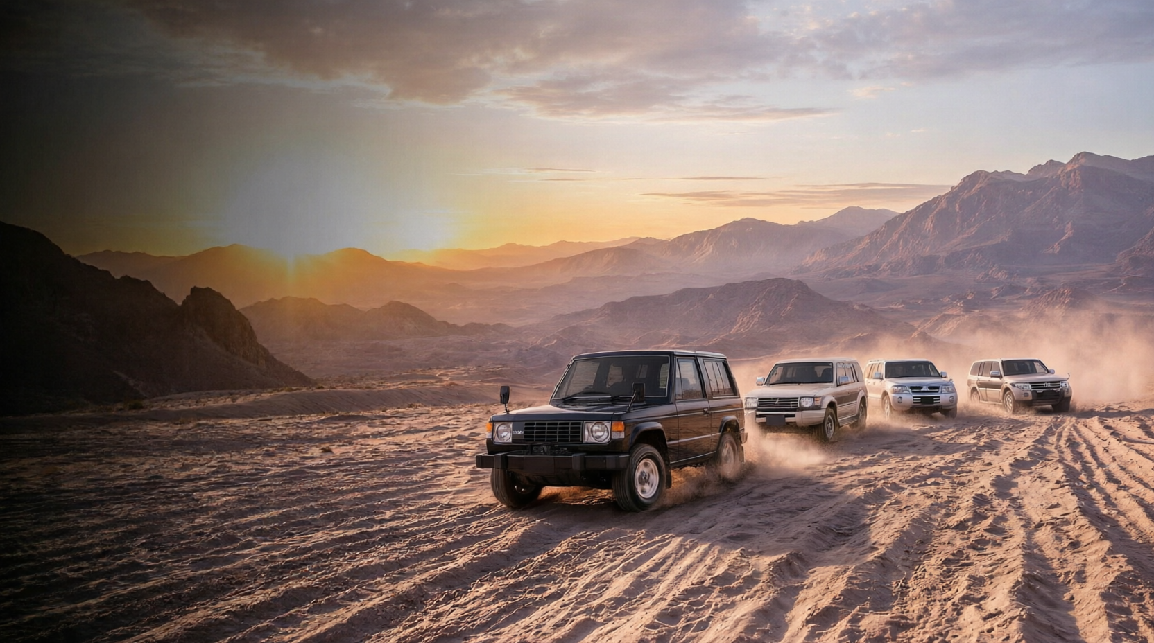 Four generations of Mitsubishi Pajero driving across desert dunes at sunrise