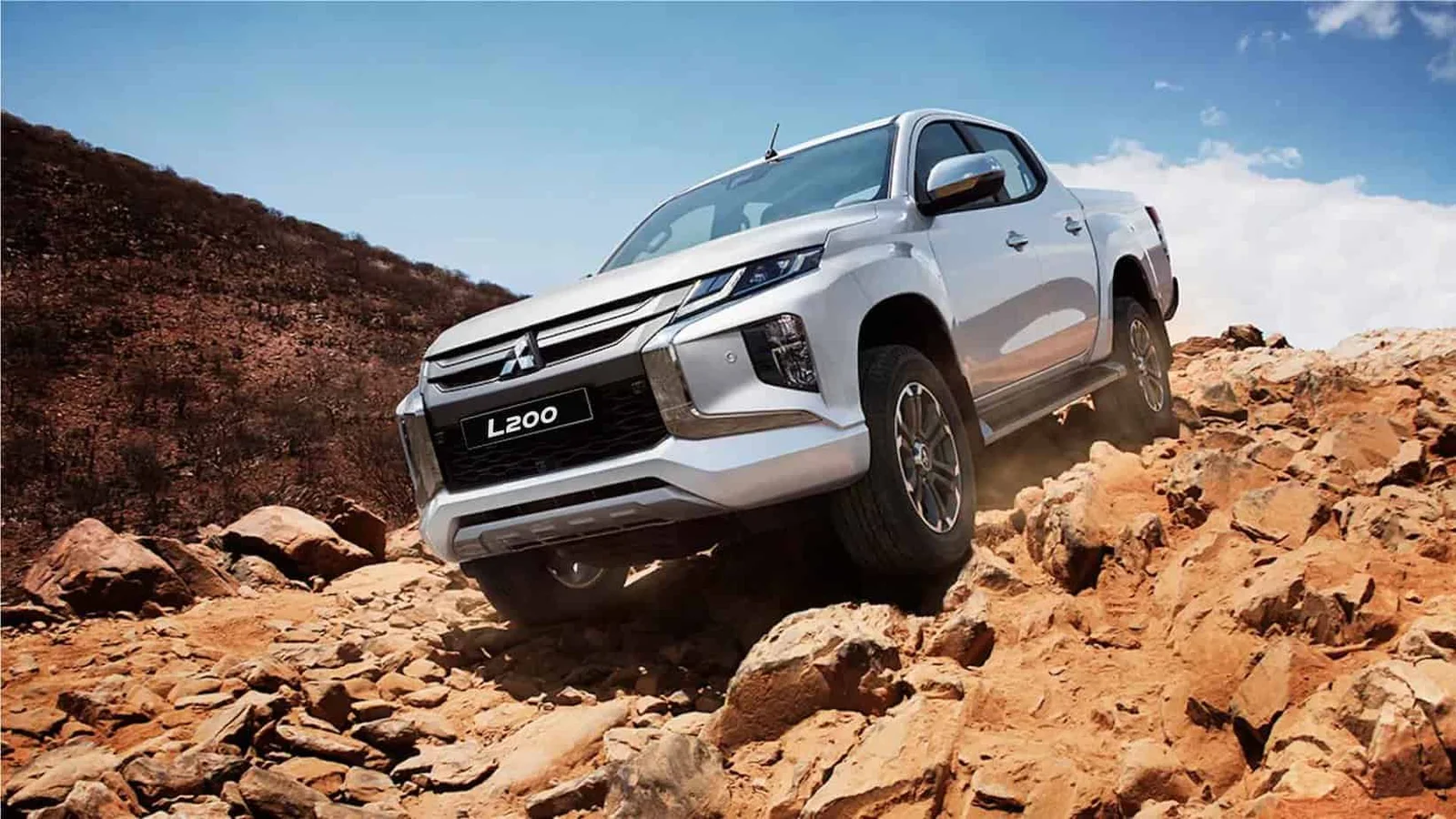 White Mitsubishi L200 climbing a rocky trail